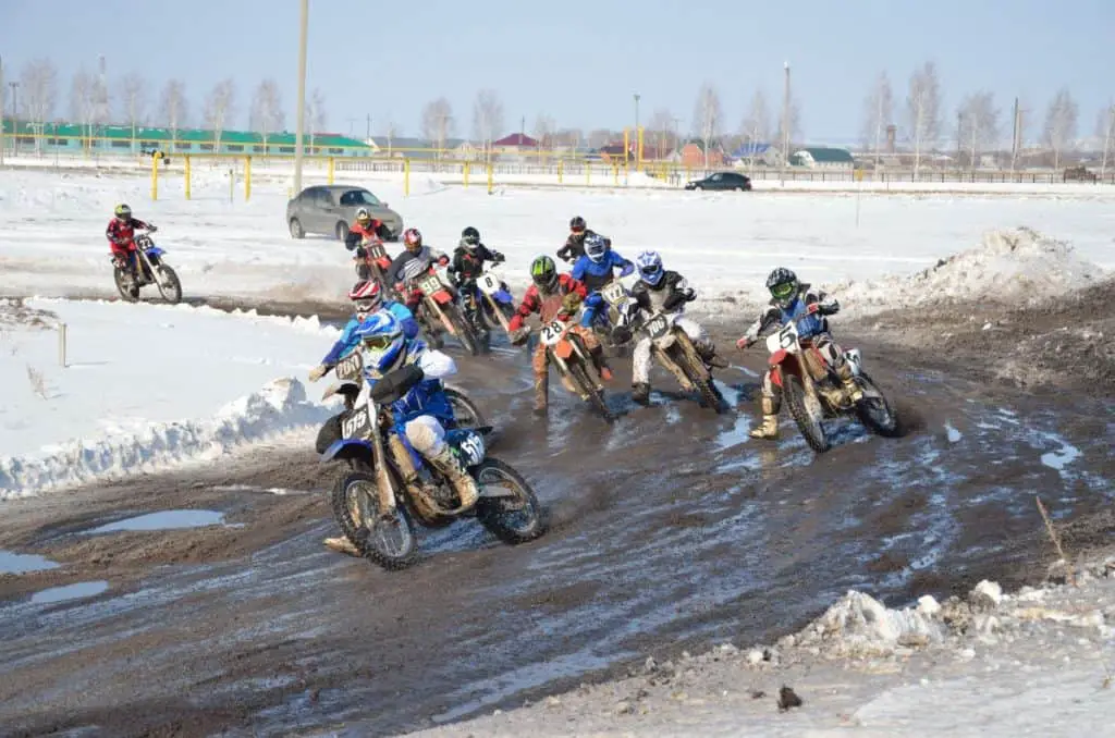 Winter motocross group of riders at the first corner after the start