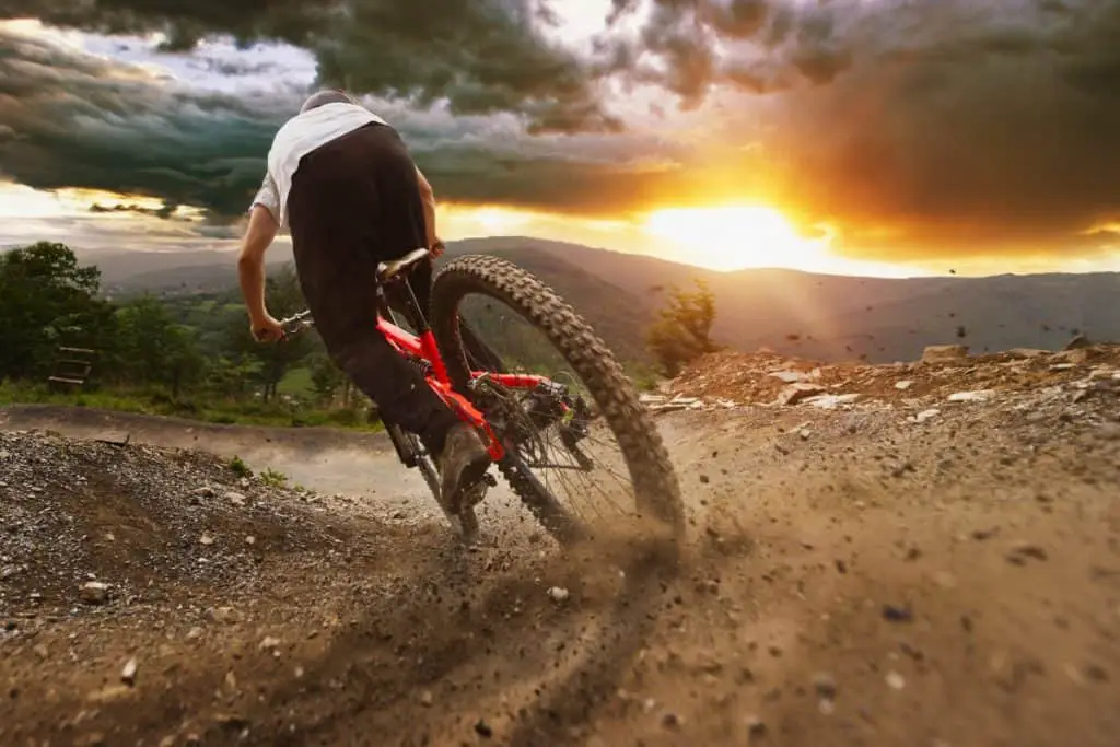 Man on mountain bike rides on the trail on a stormy sunset