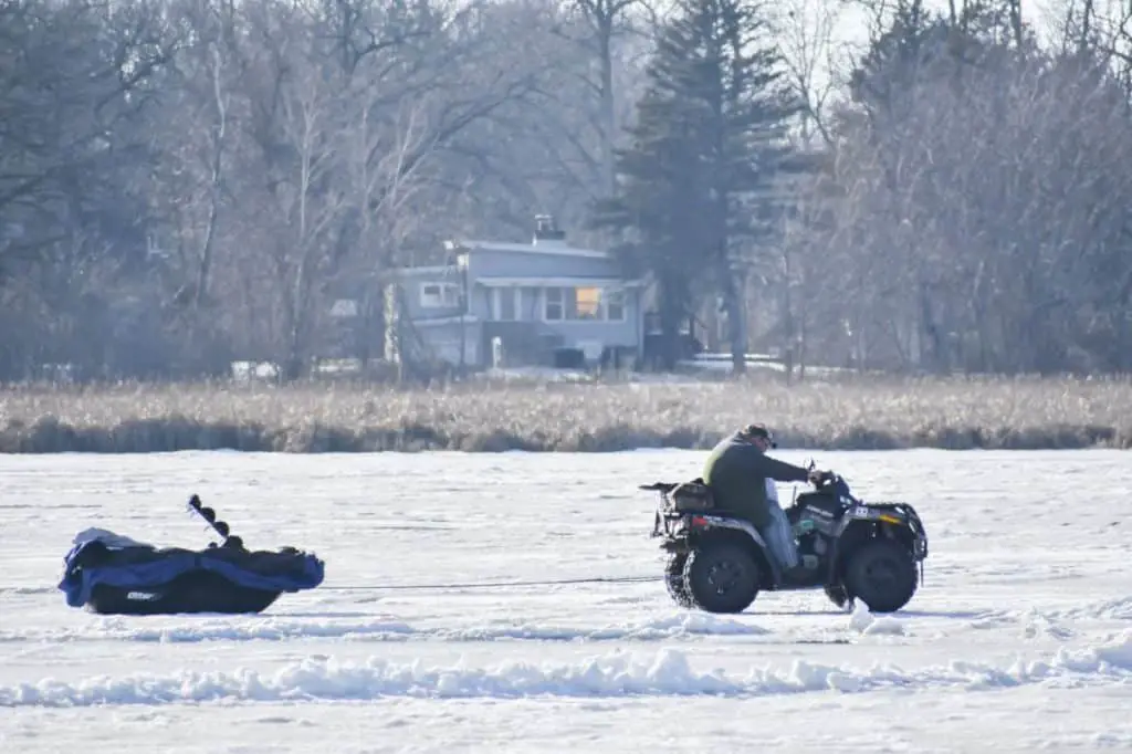 Ice Fisherman in ATV Pulling Sled of Supplies
