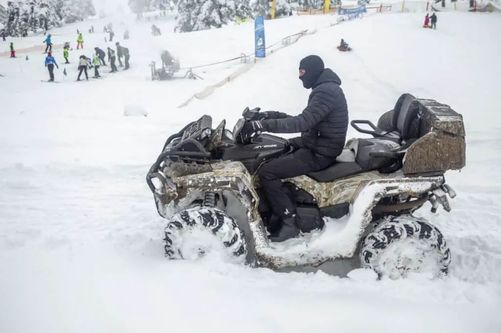 ATV driver riding through snow