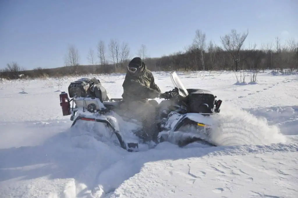 ATV on tracks ride back in a deep snow in the taiga